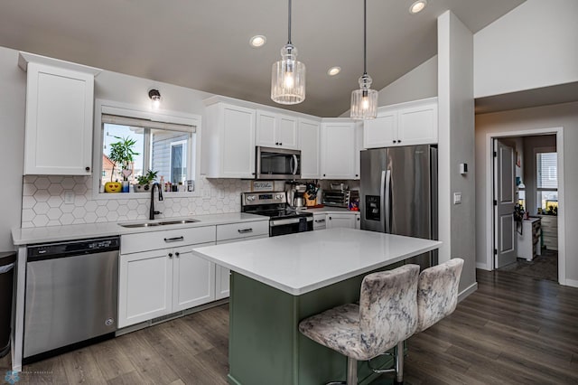 kitchen featuring vaulted ceiling, white cabinets, a kitchen island, stainless steel appliances, and sink