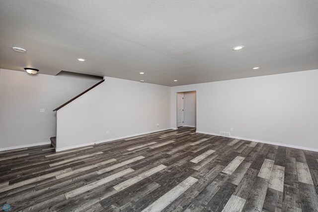 unfurnished room with a textured ceiling and dark hardwood / wood-style flooring