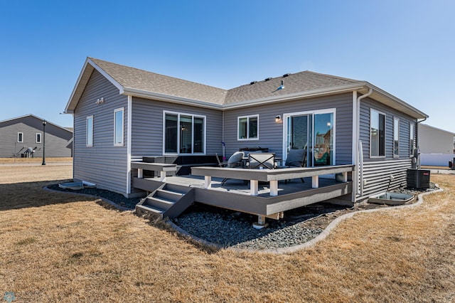 back of property featuring a wooden deck and a lawn