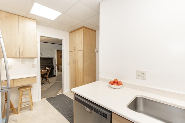 kitchen featuring a drop ceiling, dishwasher, sink, and light brown cabinets