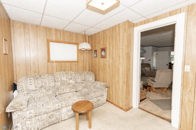 living area featuring carpet floors, wooden walls, and a drop ceiling