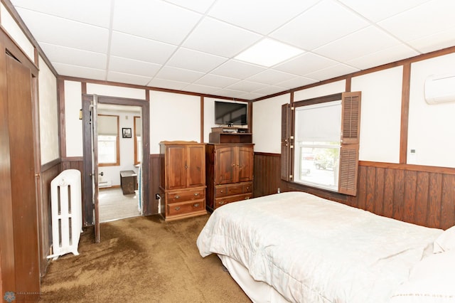 carpeted bedroom featuring wooden walls, a paneled ceiling, and radiator