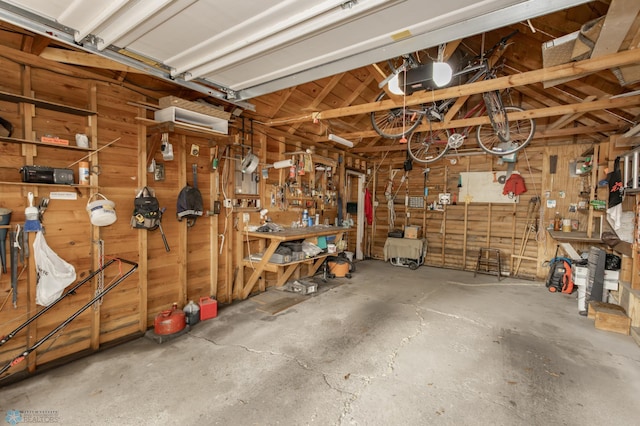 garage featuring a garage door opener, a workshop area, and wooden walls