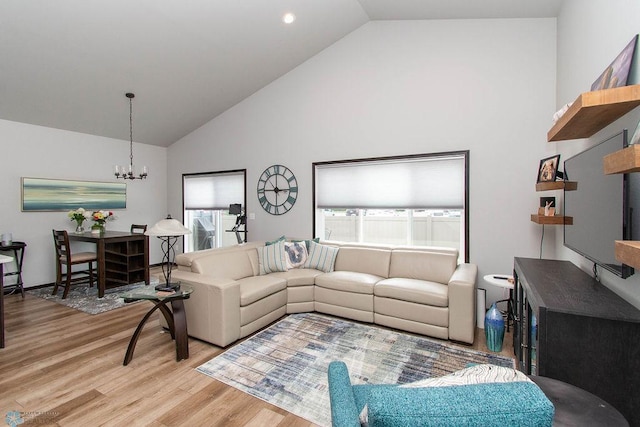 living room with light wood-type flooring, an inviting chandelier, and high vaulted ceiling