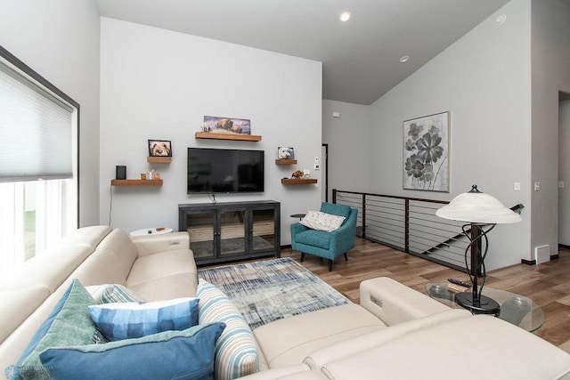 living room with hardwood / wood-style floors and high vaulted ceiling