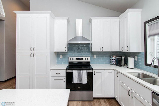 kitchen with appliances with stainless steel finishes, white cabinetry, wall chimney range hood, and lofted ceiling