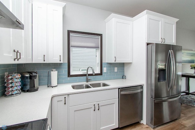 kitchen with sink, extractor fan, white cabinetry, appliances with stainless steel finishes, and light hardwood / wood-style floors