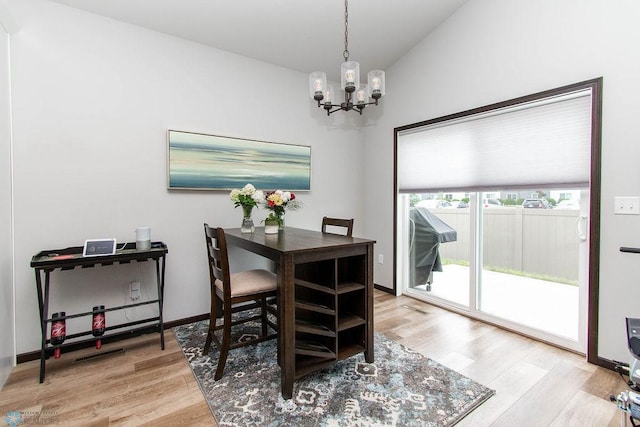 dining area featuring an inviting chandelier, wood-type flooring, and lofted ceiling