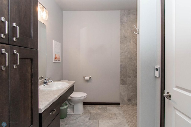 bathroom with vanity, tile patterned flooring, toilet, and tiled shower