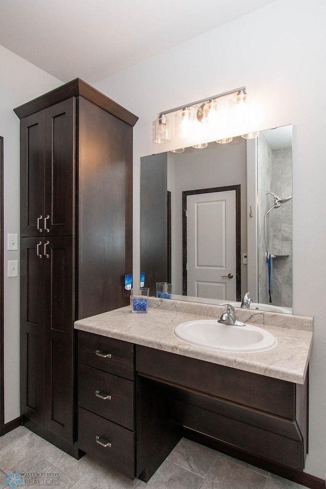 bathroom with a tile shower, tile patterned flooring, and vanity