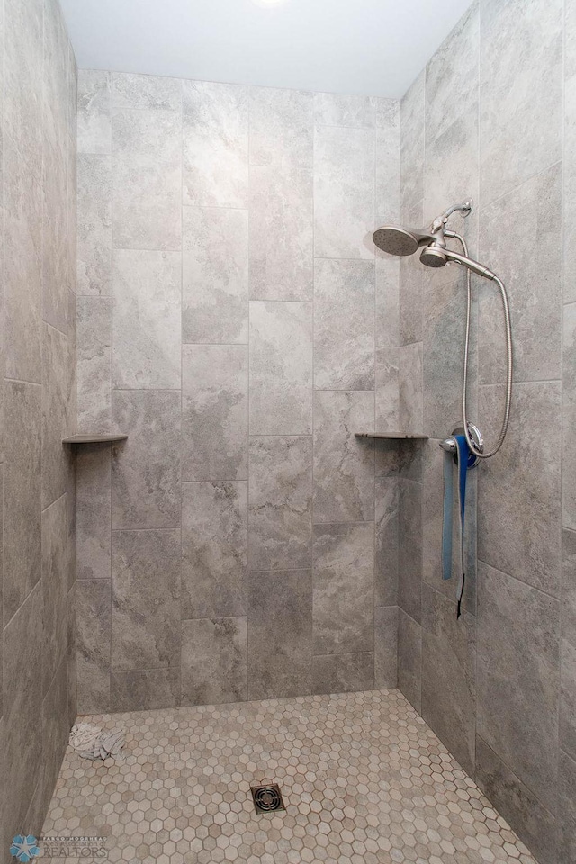 bathroom featuring ceiling fan and a tile shower