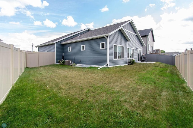 rear view of property featuring a lawn and central AC