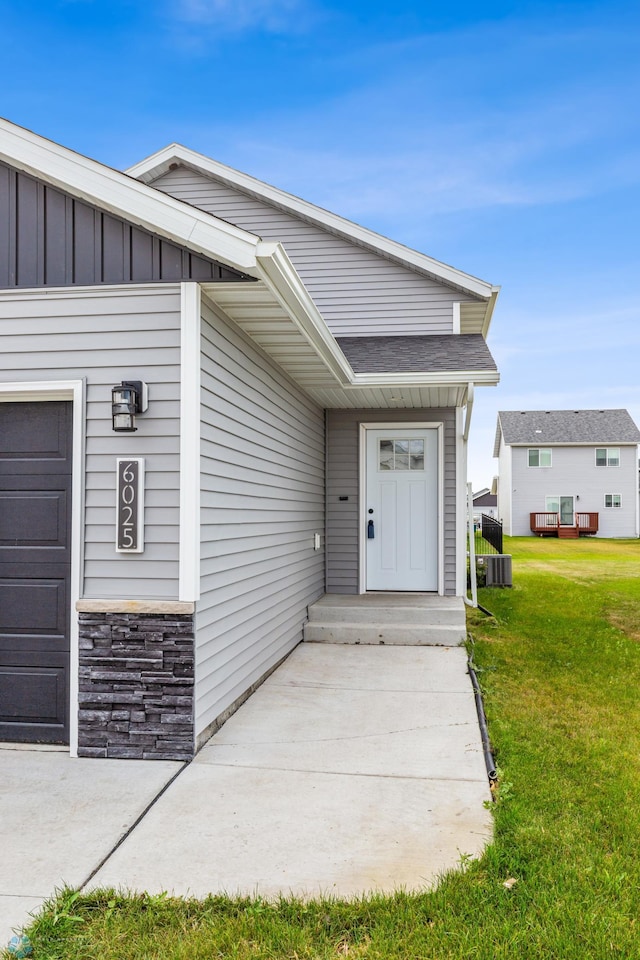 property entrance featuring a lawn and central air condition unit