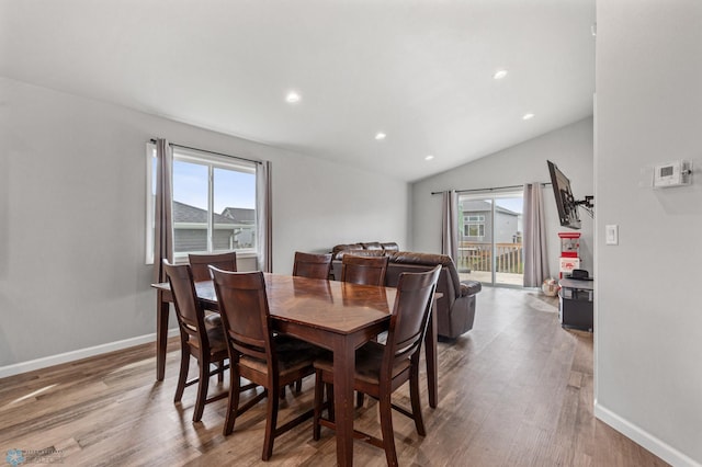 dining space featuring wood-type flooring and vaulted ceiling