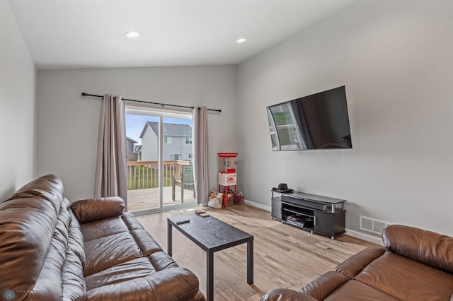 living room featuring lofted ceiling and light hardwood / wood-style flooring