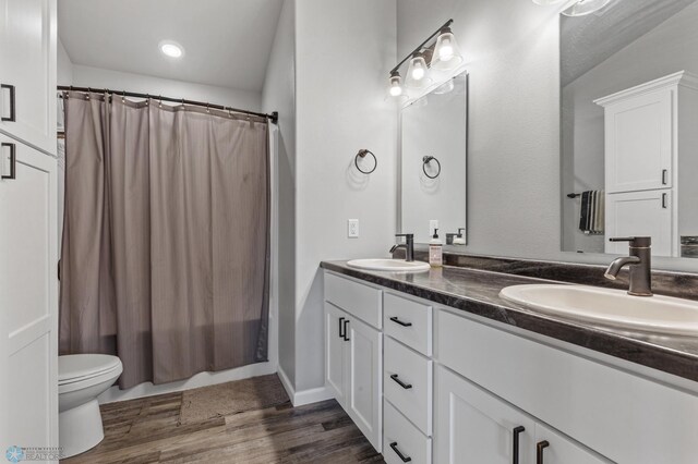 bathroom featuring hardwood / wood-style floors, walk in shower, vanity, and toilet