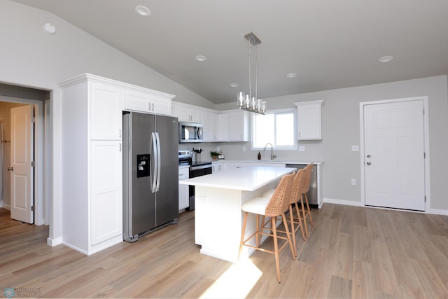 kitchen with white cabinets, stainless steel appliances, vaulted ceiling, and a kitchen island