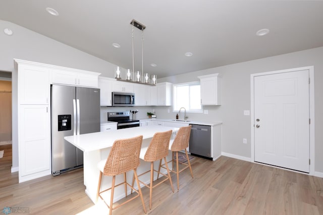 kitchen featuring hanging light fixtures, stainless steel appliances, lofted ceiling, a center island, and sink