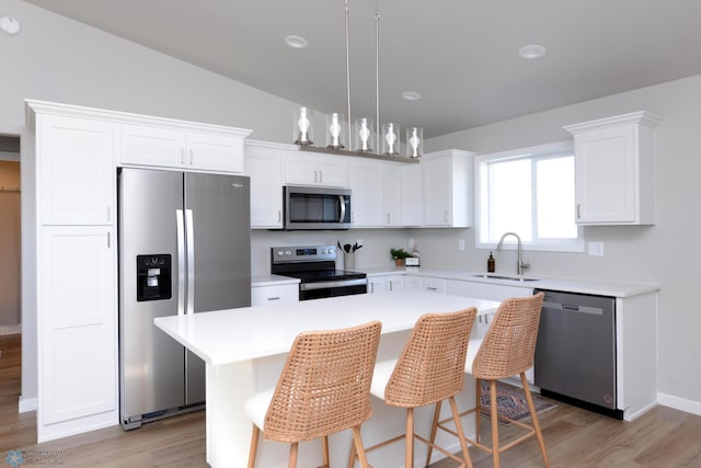 kitchen featuring sink, white cabinets, lofted ceiling, a kitchen island, and appliances with stainless steel finishes