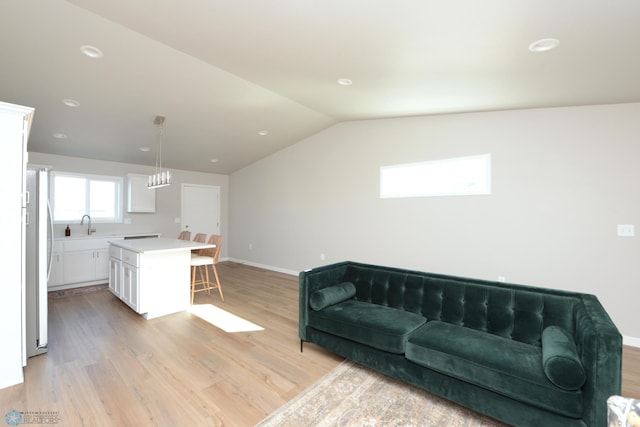 living room with light hardwood / wood-style floors, lofted ceiling, a chandelier, and sink