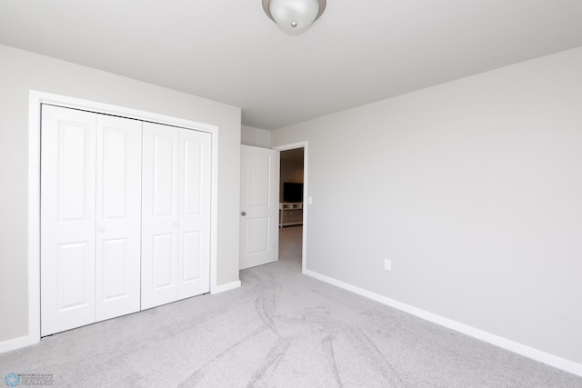 unfurnished bedroom featuring light colored carpet and a closet