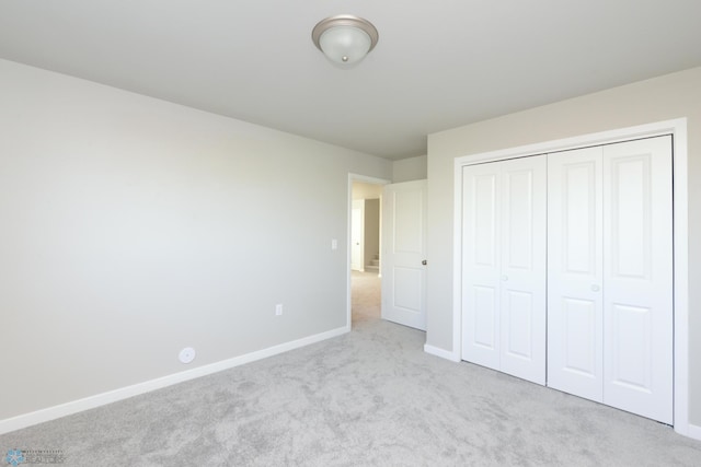 unfurnished bedroom featuring light colored carpet and a closet