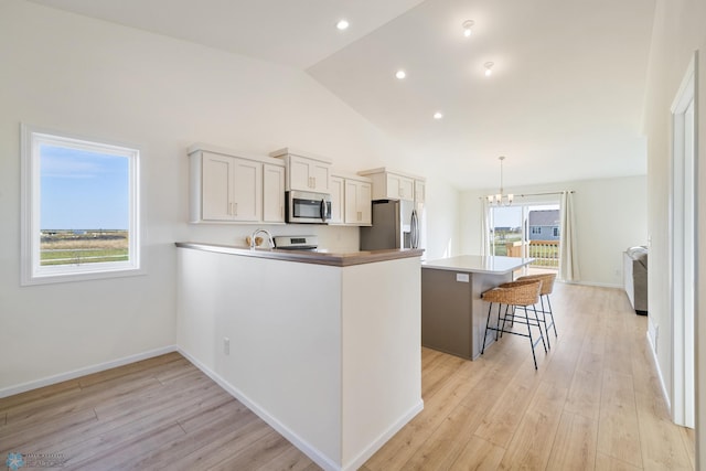 kitchen featuring a wealth of natural light, lofted ceiling, appliances with stainless steel finishes, and decorative light fixtures