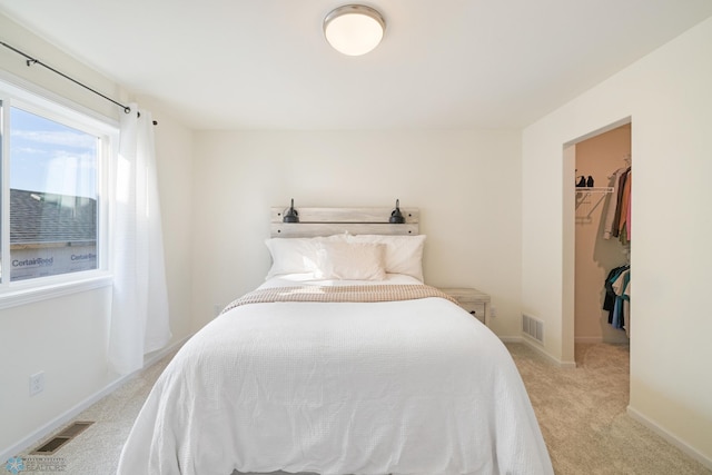 carpeted bedroom featuring a closet and a walk in closet