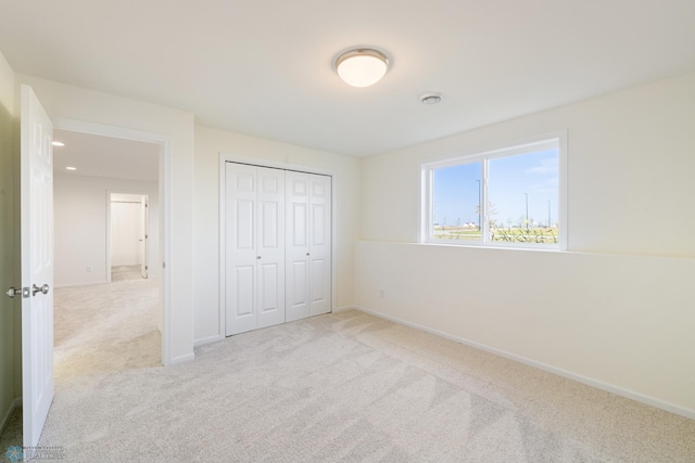 unfurnished bedroom with a closet and light colored carpet