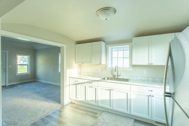 kitchen featuring a wealth of natural light, white cabinetry, white refrigerator, and sink