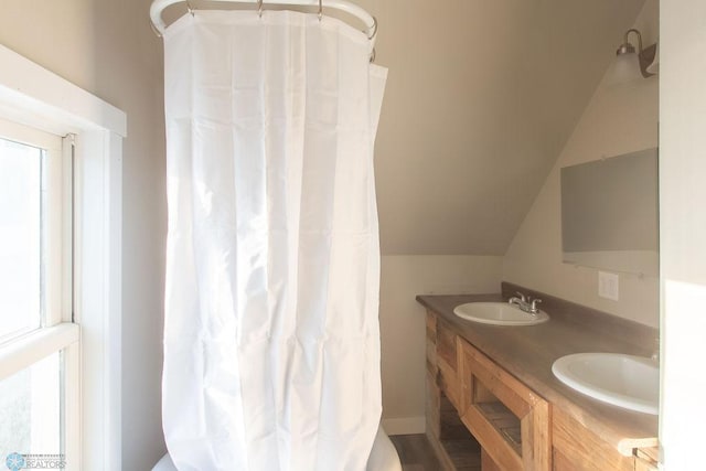 bathroom featuring a healthy amount of sunlight, lofted ceiling, vanity, and wood-type flooring