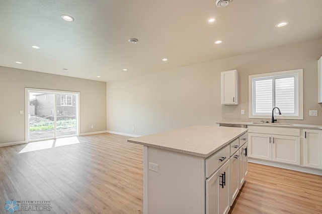 kitchen with light hardwood / wood-style flooring, a wealth of natural light, a kitchen island, and sink