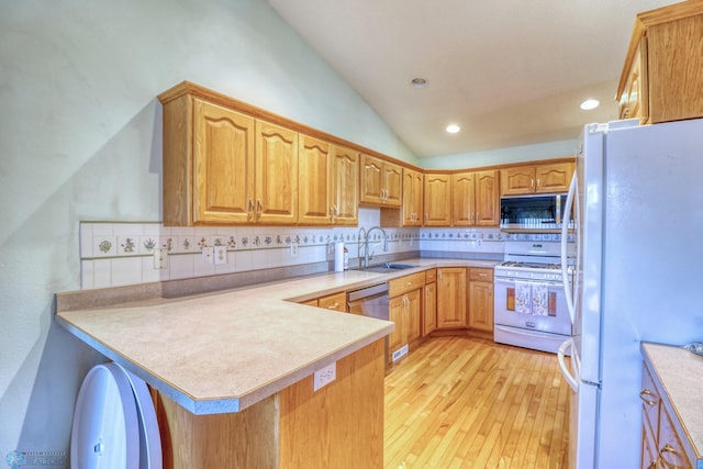 kitchen featuring tasteful backsplash, white appliances, kitchen peninsula, light wood-type flooring, and sink