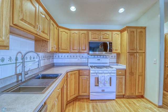 kitchen with light hardwood / wood-style flooring, tasteful backsplash, white range with gas stovetop, and sink