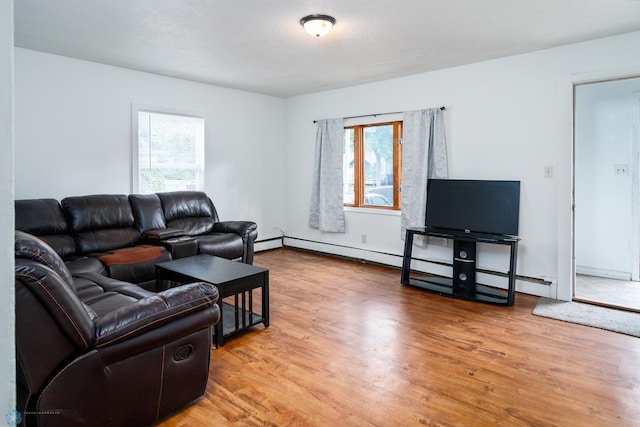 living room featuring wood-type flooring, a textured ceiling, plenty of natural light, and a baseboard heating unit