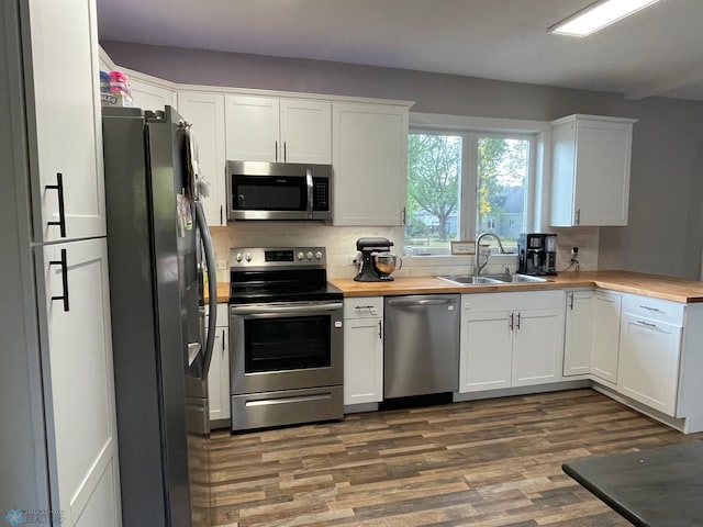 kitchen with white cabinetry, butcher block counters, sink, and stainless steel appliances