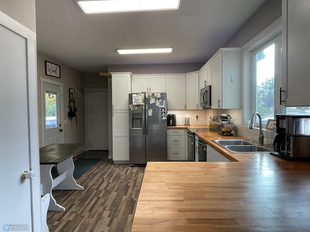 kitchen with kitchen peninsula, white cabinetry, stainless steel appliances, dark hardwood / wood-style floors, and butcher block counters