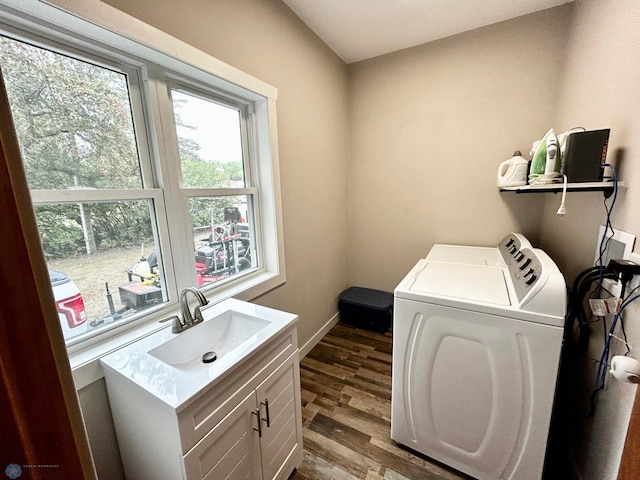 laundry room with cabinets, wood-type flooring, washing machine and clothes dryer, and sink