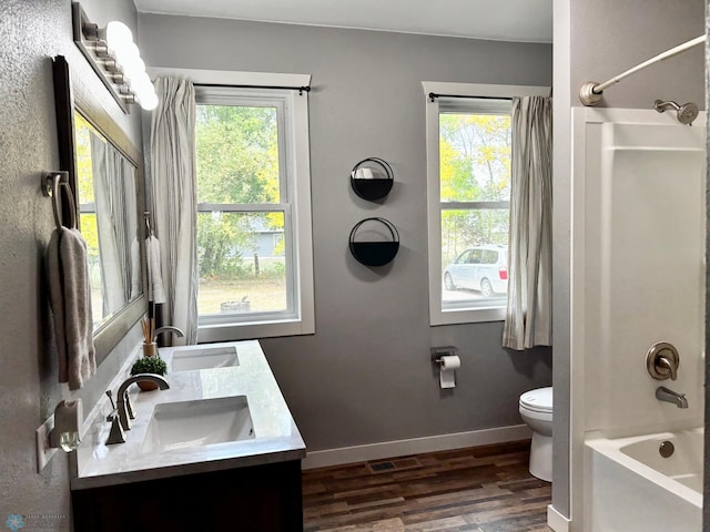 full bathroom with wood-type flooring, plenty of natural light, vanity, and toilet