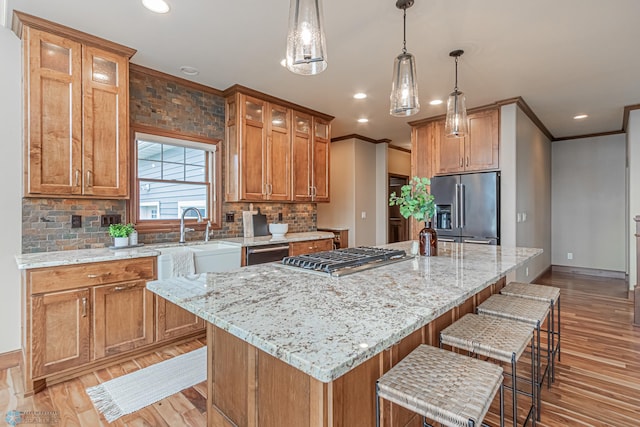 kitchen with an island with sink, hanging light fixtures, stainless steel appliances, backsplash, and ornamental molding