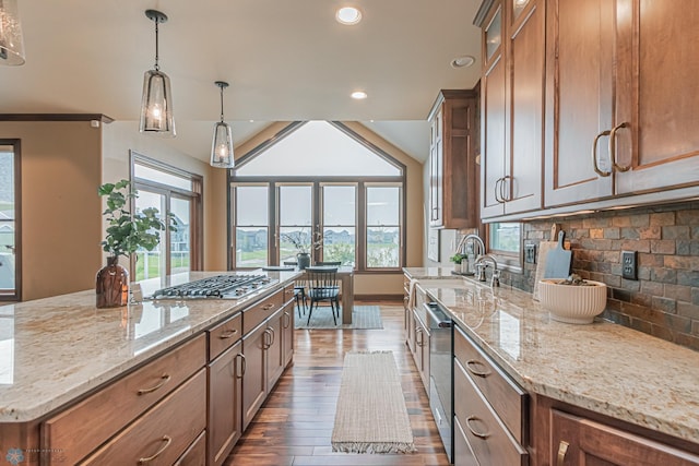 kitchen featuring light stone counters, pendant lighting, dark wood-type flooring, appliances with stainless steel finishes, and decorative backsplash