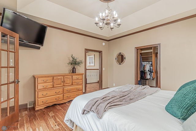 bedroom featuring light hardwood / wood-style flooring, an inviting chandelier, a closet, and a walk in closet