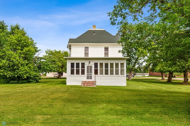 rear view of house featuring a sunroom and a yard