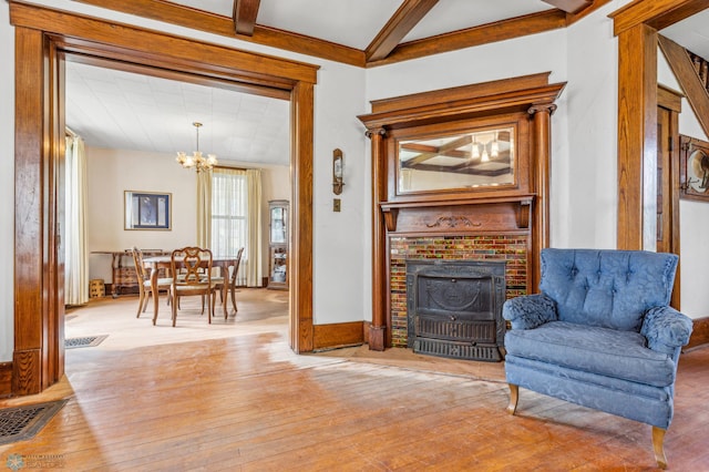 sitting room with a fireplace, light hardwood / wood-style flooring, beamed ceiling, and a chandelier