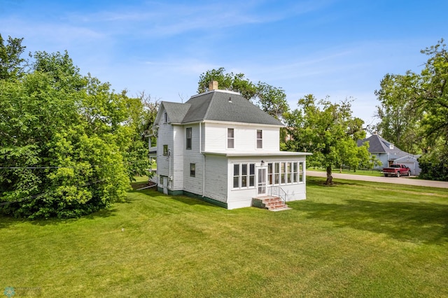 rear view of house with a lawn and a sunroom