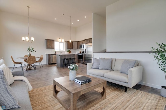 living room with a towering ceiling, a chandelier, and hardwood / wood-style flooring