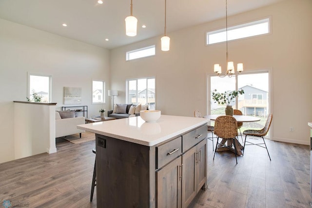 kitchen featuring hanging light fixtures, a center island, a towering ceiling, and dark wood-type flooring