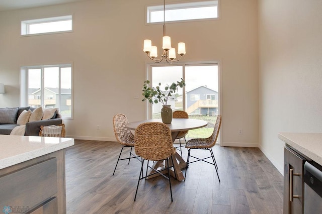 dining room with a towering ceiling, a chandelier, and dark hardwood / wood-style flooring