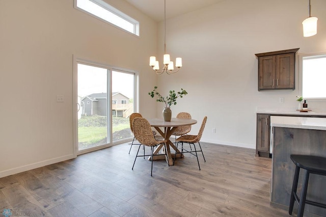 dining space with light wood-type flooring, a high ceiling, and an inviting chandelier