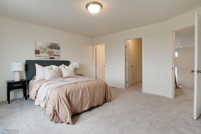 bedroom with light colored carpet, a closet, and a walk in closet